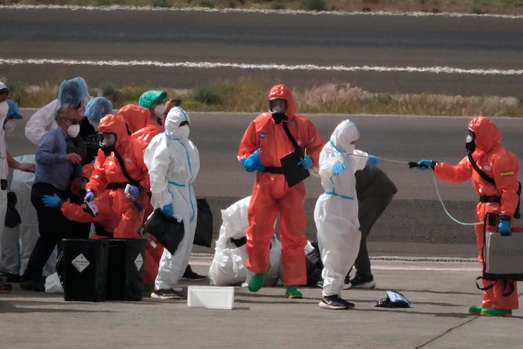Passengers are sprayed with disinfectant by Spanish government officials before boarding a plane after disembarking from the hantavirus-stricken cruise ship MV Hondius at Tenerife airport in the Canary Islands, Spain, Sunday, May 10, 2026.