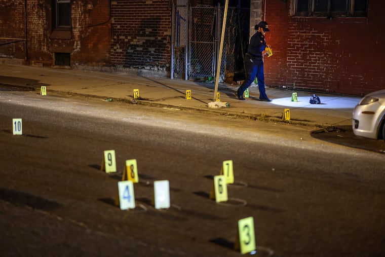 A crime-scene officer places makers on evidence on the 3900 block of Poplar Street in West Philadelphia where an 18-year-old man was fatally shot around 7:30 p.m., Tuesday, May 25, 2021. A 15-year-old boy was fatally shot about a half-hour later in North Philadelphia.