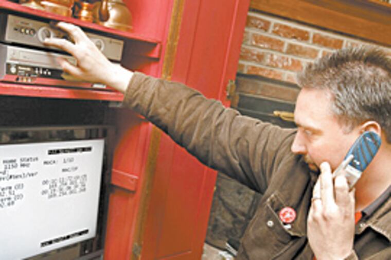 Technician Dean Pettit checks a Verizon high-definition box after putting it in a Middletown, Pa., home. The resident also got Internet and phone service with Verizon FiOS. (Michael S. Wirtz/Inquirer)
