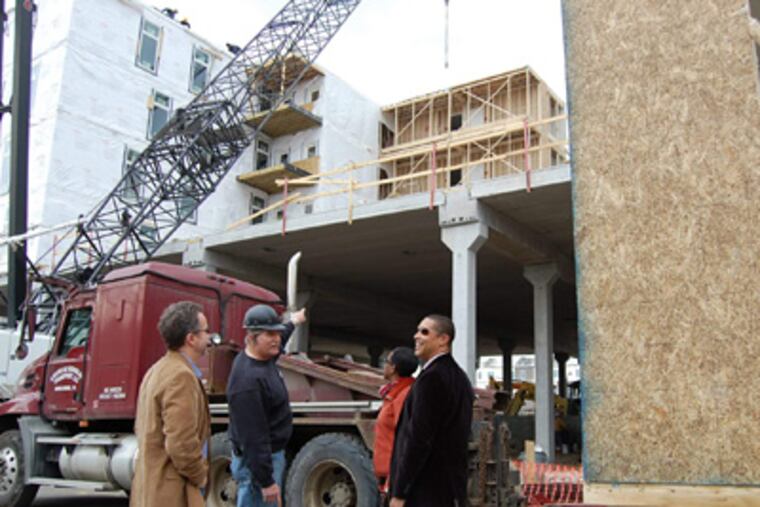 Standing near a crane that lifts 50,000-pound building modules into place at the Diamond Green Apartments complex are (from left) Jon Orens, Scott Orens, Leslie Smallwood-Lewis, and Gregory Reaves. (ALAN J. HEAVENS / Staff)