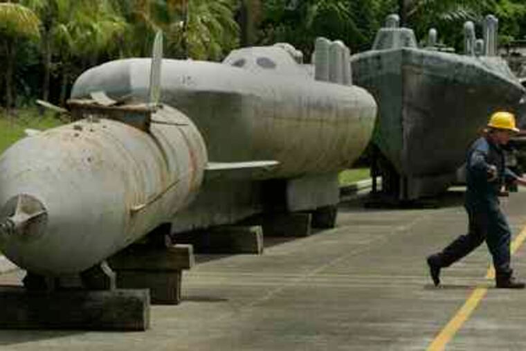 A sailor walks past homemade semi-submersible vessels, seized on land by Colombian authorities from alleged drug traffickers, at the Bahia Malaga Navy base on Colombia's Pacific coast. Twenty-three semi-subs have been captured in the last three years.