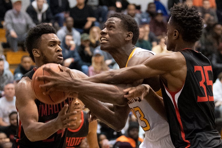 Roman Catholic's Jalen Duren (center) gets fouled by Imhotep Charter's Donta Scott (left) and Kam Roundtreem in 2018.