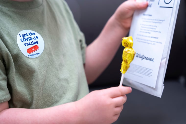 A 3-year-old holds a lollipop after receiving the Moderna COVID-19 vaccination at a Walgreens pharmacy in Lexington, S.C.