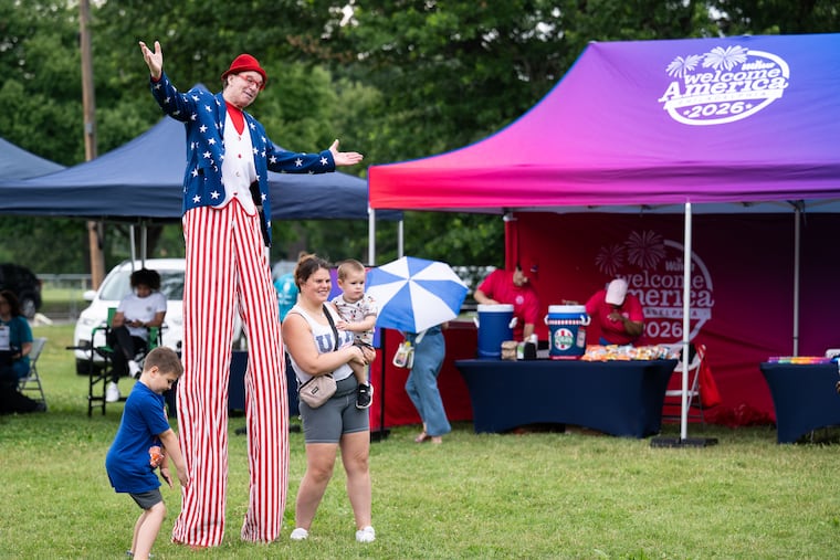 Attendees pose with a performer on stilts at the WaWa Welcome America media preview for the Philly Fair 250 outside of the Please Touch Museum in West Philadelphia on Thursday, June 18, 2026.