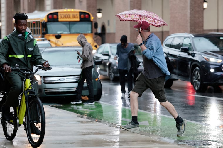Pedestrians scurry in the rain near Franklin Field last month. The forecast suggests that keeping umbrellas handy would be wise.