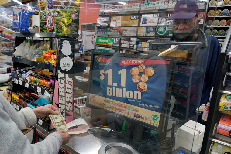 A Mega Millions customer purchases her tickets for the lottery's estimated jackpot of $1.1 billion at a convenience store in Pittsburgh Monday.