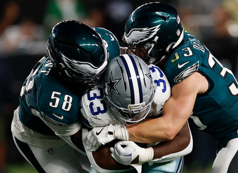 Eagles linebacker Jalyx Hunt (left) and cornerback Cooper DeJean stop Dallas Cowboys running back Javonte Williams in the season opener.