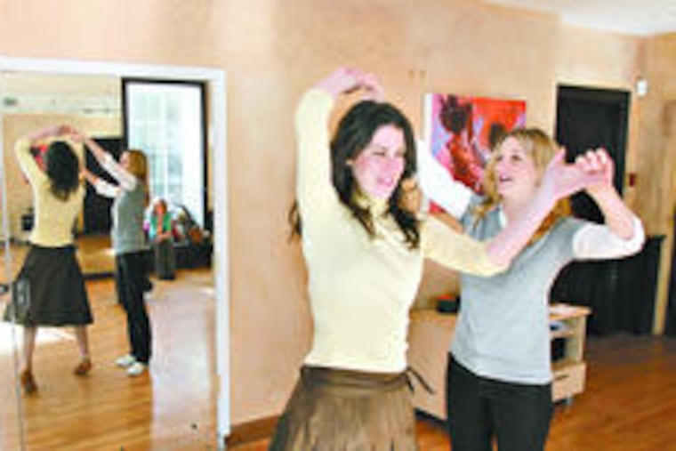 Groom-to-be Quinn Martin watches as instructor Kate Slovich (left) shows him his moves with fiancee Ashley Primis at Society Hill Dance Academy.