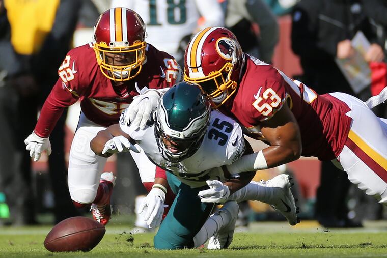 Eagles running back Boston Scott (35) fumbles the ball under pressure from Washington Redskins defensive back Jimmy Moreland (32) and inside linebacker Jon Bostic (53) during the first quarter.