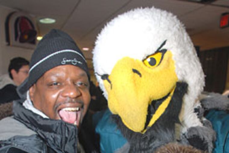 Hector Herrington of North Philadelphia takes a self-portrait with his cell phone with Eagle's mascot Swoop during a team rally in the Penn Center concourse this morning.