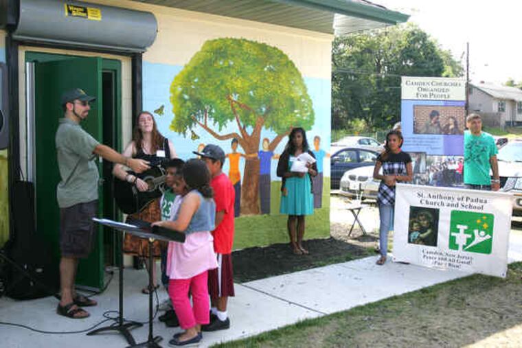 Anna Perkins of Camden Churches Organized for People leads a song about peace at the dedication of the mural at Von Nieda Park in Cramer Hill.
