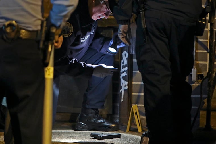 Investigators examine a gun found at the shooting scene on April 17, 2015, in Frankford. (Joseph Kaczmarek/For the Inquirer)