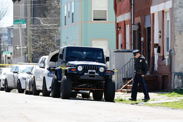 A Philadelphia police officer examines the scene of a fatal multiple shooting along the 1900 block of North 19th Street in North Philadelphia on Sunday. Police said two men were killed and two injured.