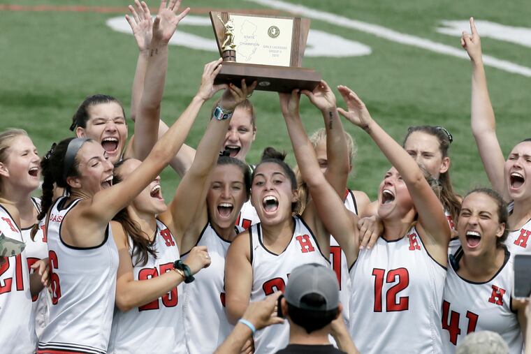 The Haddonfield girls' lacrosse team celebrates with the championship trophy after beating Madison.