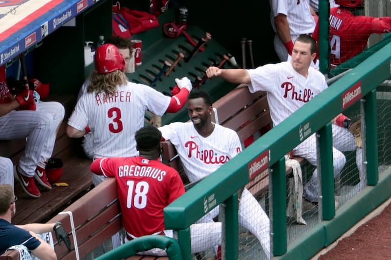 Phillies catcher J.T. Realmuto gives a virtual fist-bump to Bryce Harper during an intrasquad game Wednesday at Citizens Bank Park.