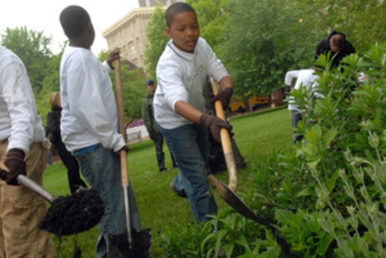 Jordan Ross (facing camera), 10, of Germantown, helps his fellow participants in the First Bloom program tidy up a planting bed on the grounds behind Carpenters Hall.