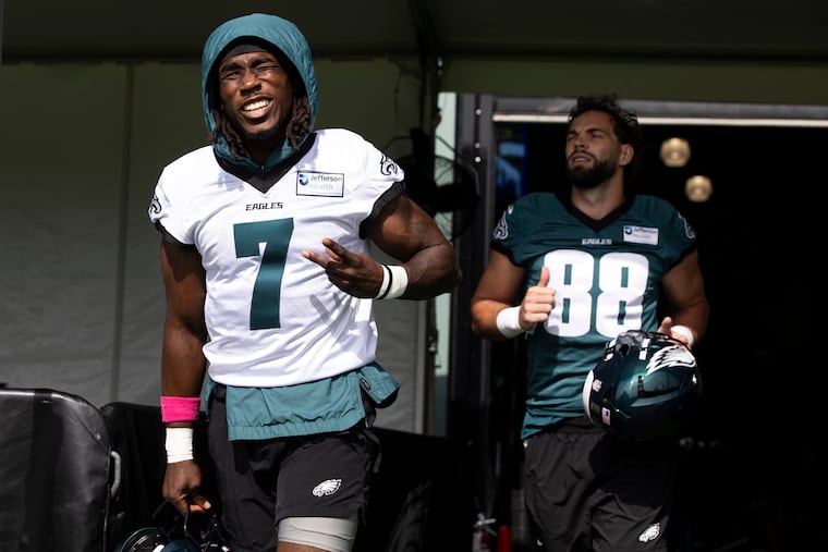 Eagles cornerback Kelee Ringo smiles while taking the field during the first day of training camp, with Dallas Goedert behind him.