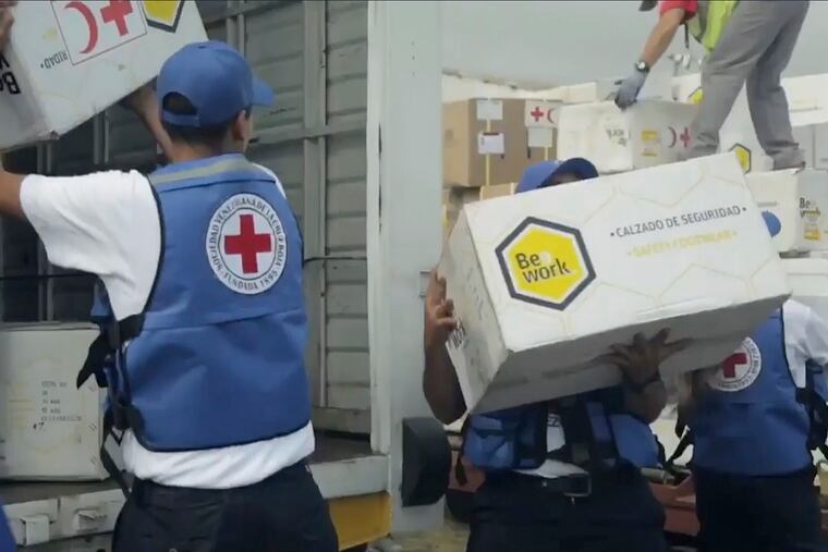 In this image taken from video provided by the International Red Cross, volunteers load into waiting vehicles the first shipment of humanitarian aid from the International Federation of Red Cross and Red Crescent Societies at the Simon Bolivar International Airport in Maiquetia, Venezuela, Tuesday, April 16, 2019. The Red Cross announced in late March that it had obtained permission from officials to begin delivering assistance to the crisis-stricken country. (International Committee of the Red Cross via AP)