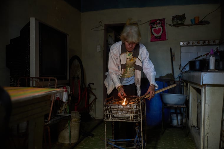 Minorkys Hoyos Ruiz lights coals to cook dinner during a scheduled blackout to ration energy in Santa Cruz del Norte, home to one of Cuba’s largest thermoelectric plants