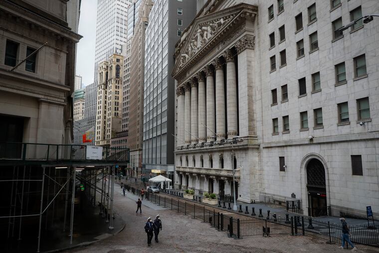 NYPD officers walk along a sparsely populated Wall Street.