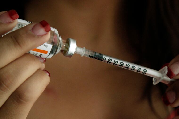 A teen fills a syringe as she prepares to give herself an injection of insulin at her home.