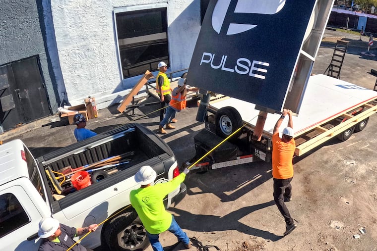The sign for the Pulse nightclub is removed by workers, Wednesday, March 11, 2026, at the memorial site of the 2016 mass shooting in Orlando, Fla., that killed 49. The sign will be preserved and displayed at the permanent memorial, slated to open in Fall of 2027. (Joe Burbank/Orlando Sentinel via AP)