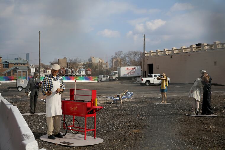 Lifelike statues by Seward Johnson stand in a lot near 48th and Market streets in West Philadelphia.