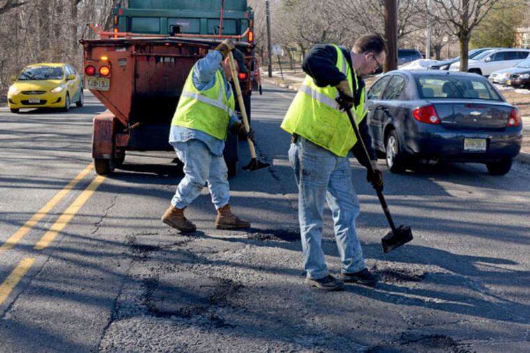 Chip Park (left) and Dave Flite, with the Camden County Public Works Department, patch potholes in front of Thomas Paine Elementary School on Church Road in Cherry Hill on March 12, 2015. ( TOM GRALISH / Staff Photographer )