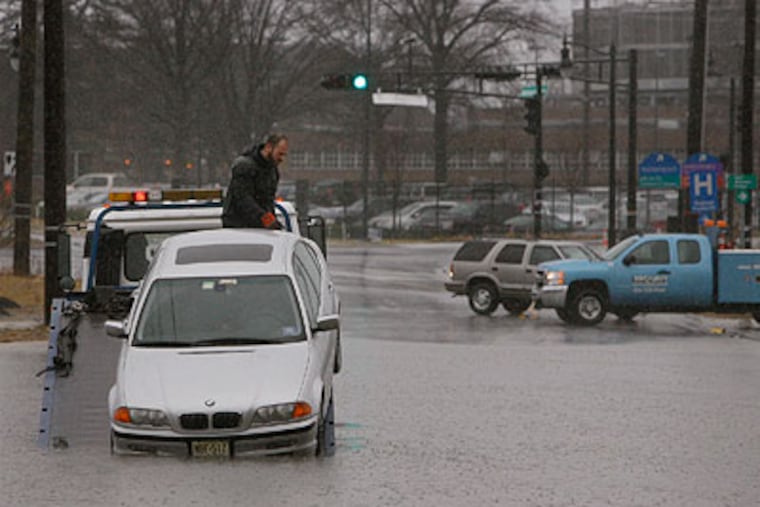 A tow truck operator removes a stranded car from a side street along Admiral Wilson Boulevard in Camden. (Michael S. Wirtz / Staff Photographer)