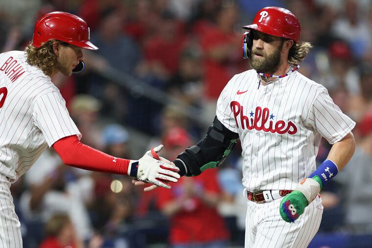 Phillies designated hitter Bryce Harper celebrates scoring a run in the third inning with Alec Bohm. Harper went 2-for-4 with a triple.