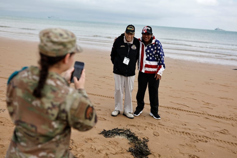 A U.S. soldier takes a photograph of American World War II veteran Sid Edson (center left) during a ceremony on Omaha Beach, Tuesday in Normandy, France. World War II veterans from across the United States, as well as Britain and Canada, are in France to mark 80 years since the D-Day landings that helped lead to Adolf Hitler's defeat.