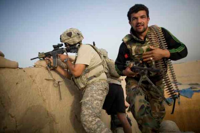 A U.S. soldier fires at insurgents as an Afghan comrade takes position during fighting in the Arghandab Valley.