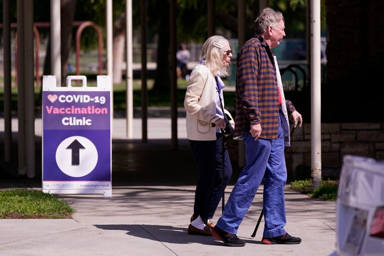 People leave a testing and vaccination clinic for COVID-19 in Long Beach, Calif.