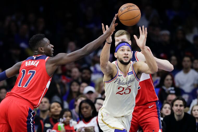 Sixers guard Ben Simmons goes after the loose basketball against Washington Wizards guard Isaac Bonga (left) and forward Davis Bertans during the third quarter on Saturday night's game at the Wells Fargo Center.