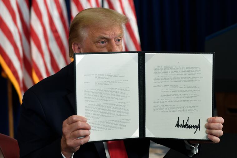 President Donald Trump signs an executive order during a news conference at the Trump National Golf Club in Bedminster, N.J., Saturday..