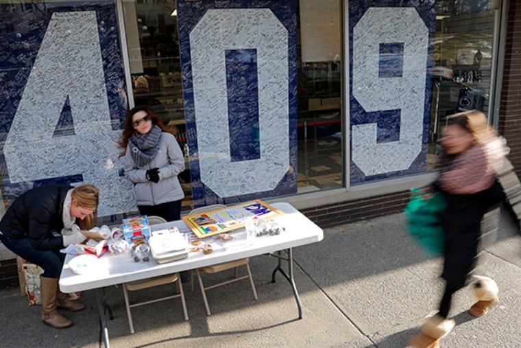 Penn State students Jackie Jones, left, of Pittsburgh, and Jacqueline Browne, center, from South River, N.J., man a bake-sale table in front of the Penn State Student Bookstore in State College, Pa., Friday, Jan. 16, 2015. (AP Photo/Gene J. Puskar)