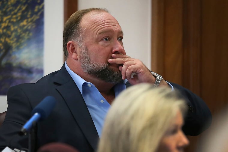 Alex Jones attempts to answer questions about his text messages asked by Mark Bankston, lawyer for Neil Heslin and Scarlett Lewis, during trial at the Travis County Courthouse in Austin, on Wednesday.