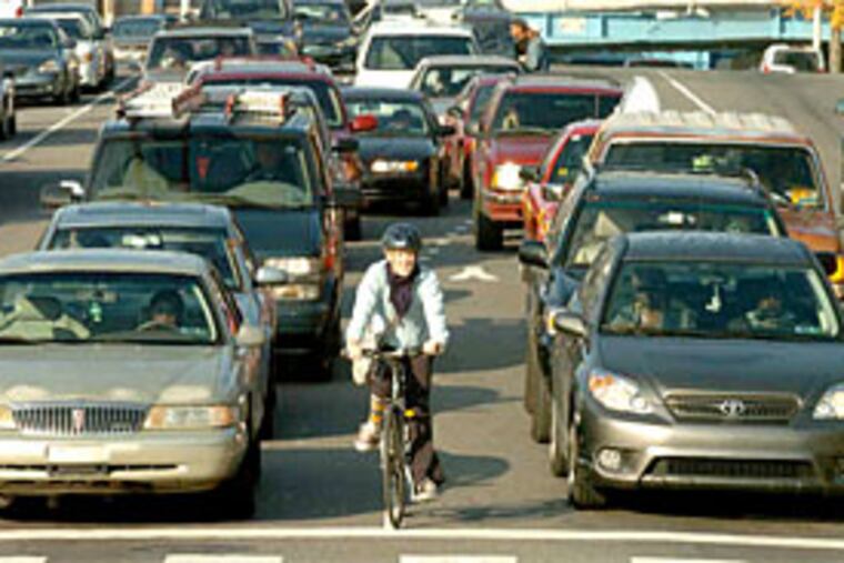 By car and by bike , workers stranded by the SEPTA strike head into town at 44th and Market Streets during yesterday's morning rush. (Clem Murray / Staff Photographer)