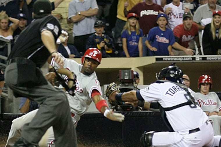 The Phillies' Jimmy Rollins scores as Padres catcher Yorvit Torrealba misses the tag. (AP Photo/Gregory Bull)