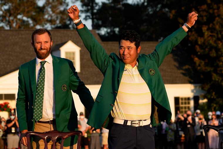 Hideki Matsuyama puts on the champion's green jacket after winning the Masters as Dustin Johnson watches on Sunday.