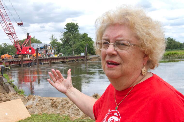 Irma Stevenson, of E. Jefferson St, recalls the 2012 train derailment during an interview at her home which on the Mantua Creek in very close proximity to the site of the accident. Workers can be seen on the rail bridge in background in Paulsboro, July 29, 2014. ( DAVID M WARREN / Staff Photographer )