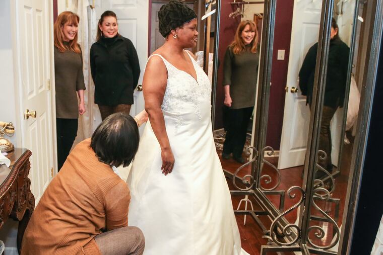 Sharon Suleta (top left) and Carolyn Verdi (top right) watch as seamstress Mira Dieterle fits Maria Isaacs' wedding gown.