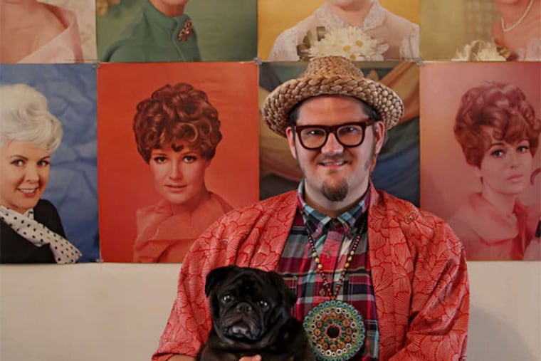 Jay McCarroll, with his dog Vernon and his collection of 1960s hairdo portraits he found at a vintage shop in South Philly.