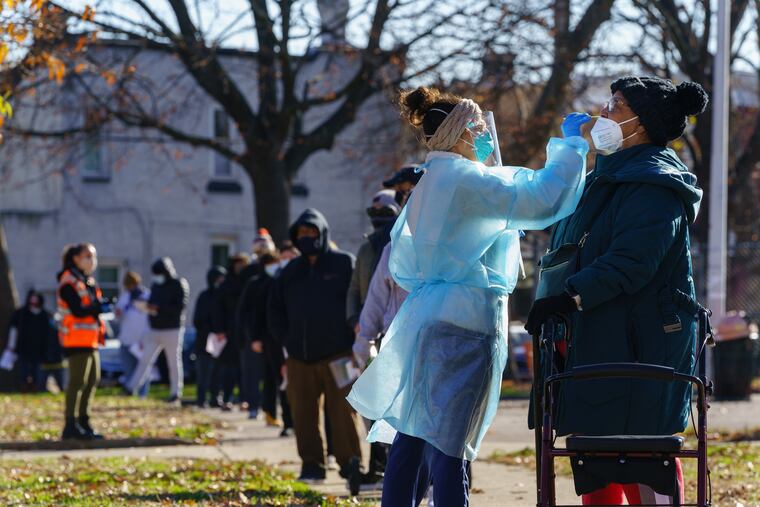 Registered nurse Laura Moore, center, swabs a patient during testing for COVID-19, at a community testing site organized by Philadelphia FIGHT Community Health Centers, at Mifflin Square Park on Dec. 10 in south Philadelphia. Philadelphia FIGHT provides low-barrier testing in neighborhoods throughout Philadelphia. Visitors do not need an appointment, insurance, ID, or COVID-19 symptoms to get tested.