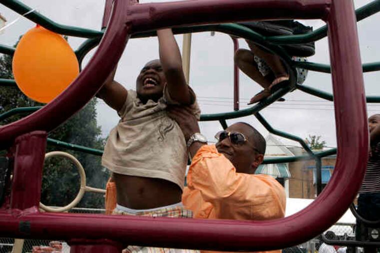 Carl Boddie helps Wayne Styles , 7, with a pull-up on the 2500 block of Napa Street in Strawberry Mansion. Few Good Men held its third annual Father's Day community cookout there yesterday.
