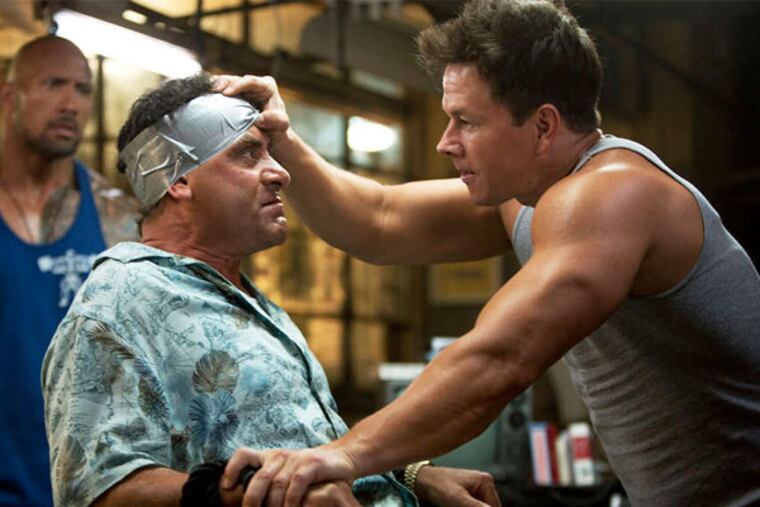 Mark Wahlberg (right) plays a gym trainer who loses control, with Tony Shalhoub (center) and Dwayne Johnson, in "Pain & Gain."