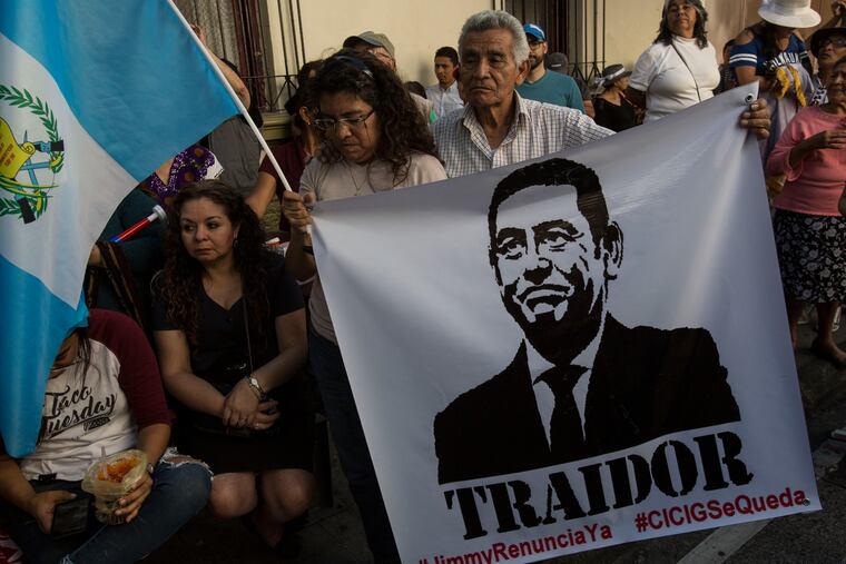 Demonstrators demand the resignation of Guatemalan President Jimmy Morales, featured in the poster that reads in Spanish "Traitor," outside the Presidential House in Guatemala City, Saturday, July 27, 2019. Demonstrators are protesting an agreement that their government signed with Washington to require migrants passing through the Central American country to seek asylum there, rather than pushing on to the U.S.