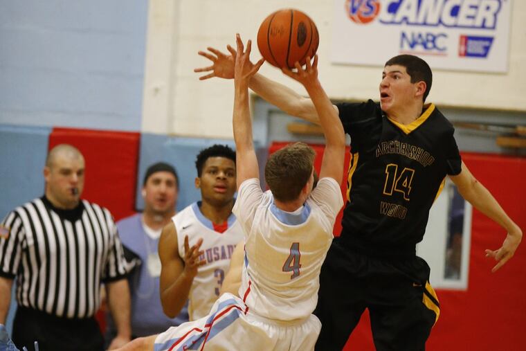 Archbishop Wood’s Andrew Funk, right, tries to interfere with a shot by Father Judge’s Mike Power in Catholic League contest last season. ( CHARLES FOX / Staff Photographer )