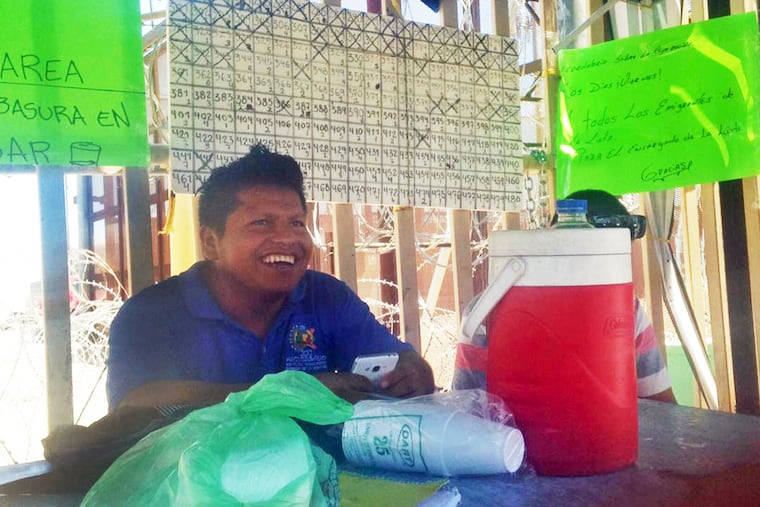 In this July 2, 2019 photo provided by Jesse Tellera, asylum seeker Claudio Aviles sits by a posted list of migrants who are in San Luis Río Colorado, Mexico, waiting to seek asylum in the United States. Aviles, of Guerrero, Mexico, has since made it to the U.S. with his wife and young children. Thousands of asylum seekers are waiting on the Mexican side of the border to ask for asylum in the U.S., which has severely restricted the number of people it allows in each day.