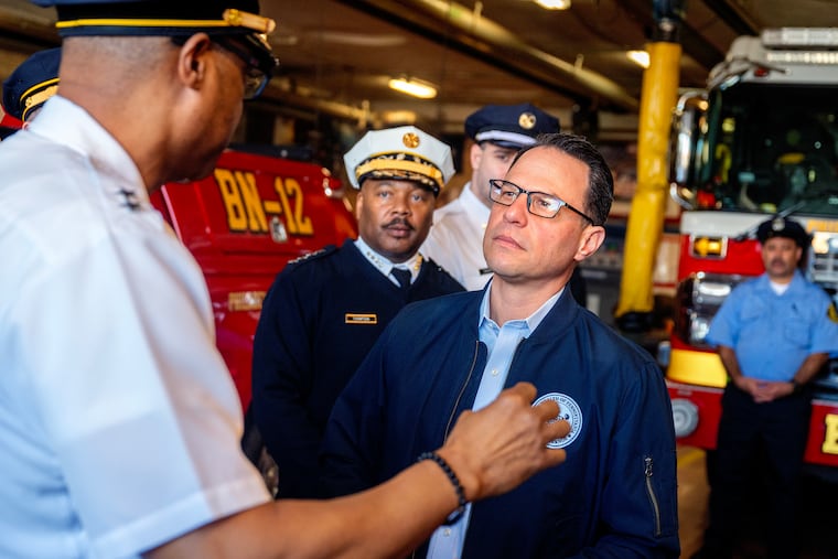 Philadelphia Fire Deputy Commissioner for logistics Carl Randolph (left) describes the scene that night as Gov. Josh Shapiro visits the firefighters at Engine 71 who responded to the air ambulance plane crash along Cottman Avenue in Northeast Philadelphia.